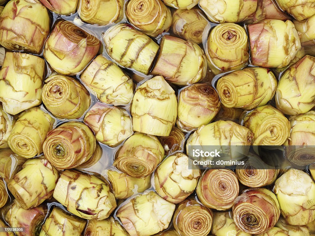 cooked and eaten "Hearts of artichokes, cleaned, cut and reduced the outer leaves and tough, rested in a solution water, lemon and vinegar, ready for cooking." Artichoke Stock Photo