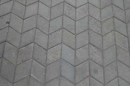 Dusty surface of gray diamond shaped concrete pavement with geometric pattern