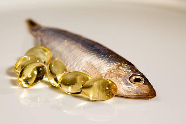 cápsulas de aceite de pescado junto a sprat - fish oil fotografías e imágenes de stock