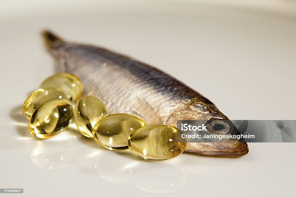 Capsule di olio di pesce accanto a sprat - Foto stock royalty-free di Olio di pesce