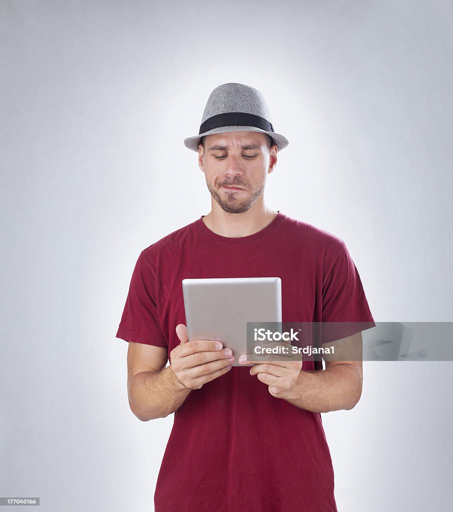 Frowned człowiek confusedly Patrząc na tablet PC z kopii przestrzeni - Zbiór zdjęć royalty-free (Codzienne ubranie)