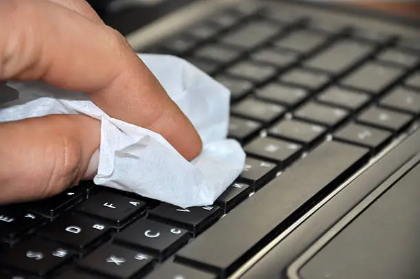 Photo of Fingers cleaning the keyboard of a digital notebook