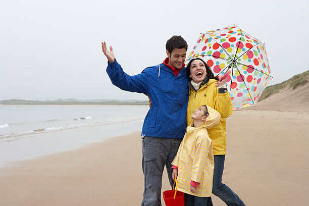 Happy family on beach with umbrella stock photo