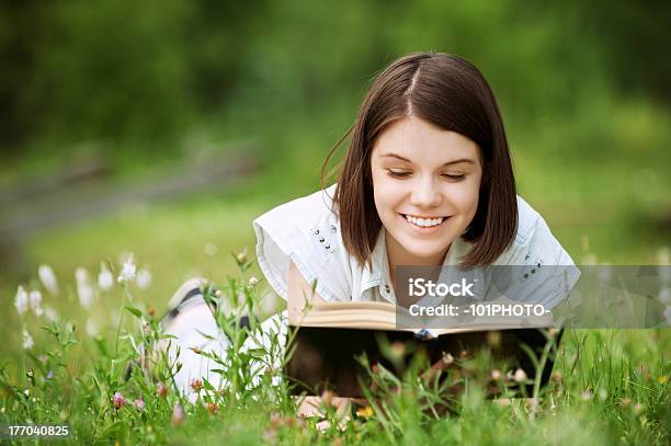 Photo libre de droit de Jeune Femme Se Trouve Sur Lherbe Et Lit Livre banque d'images et plus d'images libres de droit de Adolescence - Adolescence, Adolescent, Adulte