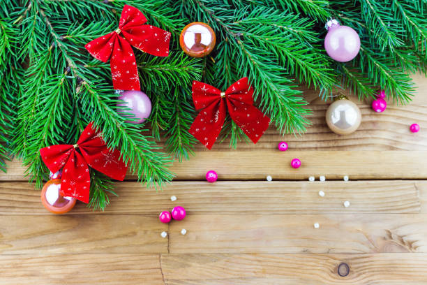 istock Christmas fur-tree branches with balls and red bows on wooden 1770410922