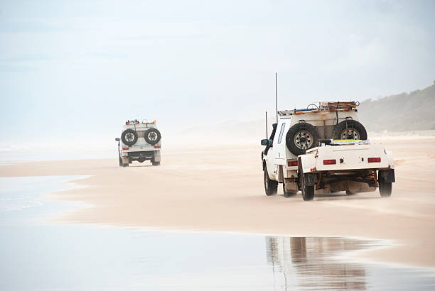 Ute trucks beach driving on tropical fraser island, australia stock photo