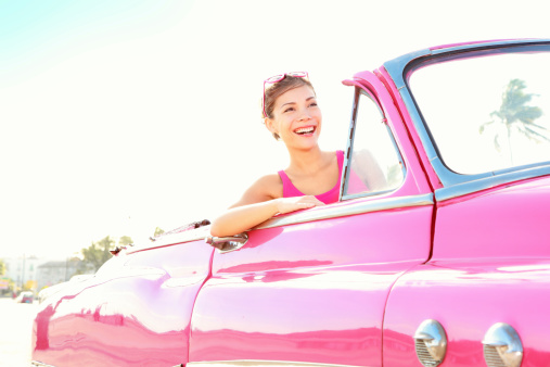 Vintage retro car xwoman driving in pink cabriolet old car smiling happy in Havana, Cuba.