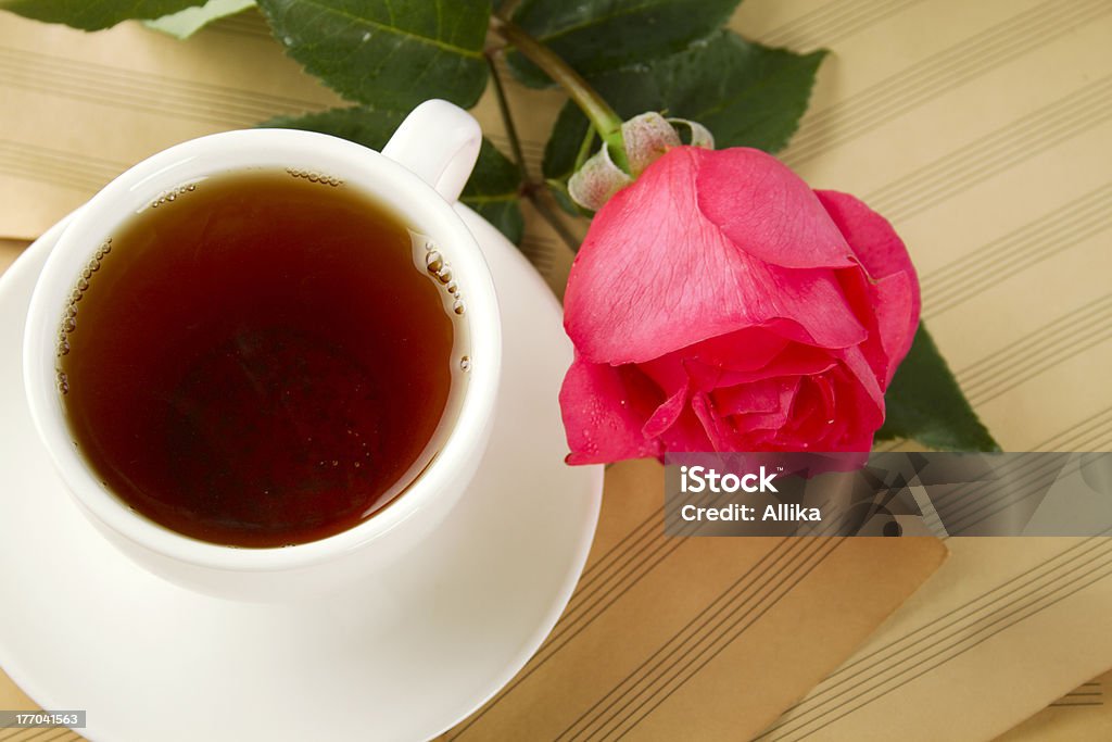 Cup of tea and rose White cup of tea next to sugar and is a beautiful red rose lying on sheets of old paper sheet music Breakfast Stock Photo
