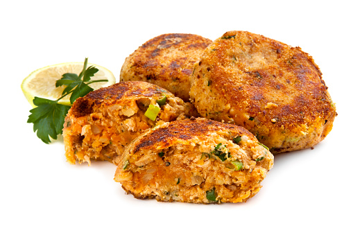 Salmon fishcakes or patties, with lemon and parsley, isolated on white background.