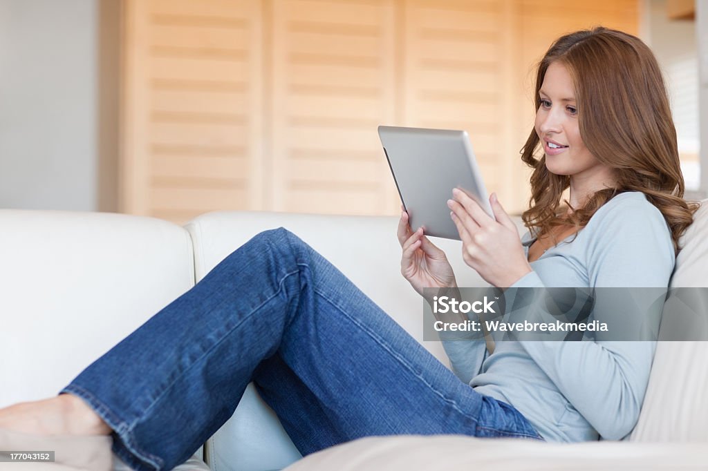 Femme lisant un e-book sur le canapé-lit - Photo de 25-29 ans libre de droits