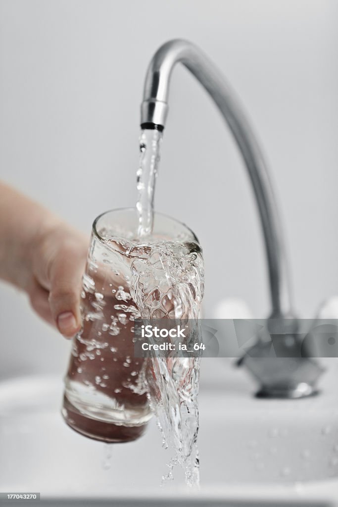 Glass pouring fresh drink water Human hand holding glass pouring fresh drink water at kitchen faucet Water Stock Photo