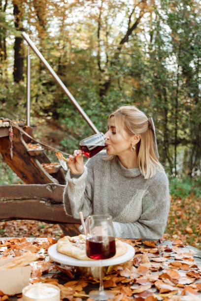 la jeune fille profite de la nature automnale. boit du vin rouge en regardant la forêt autour - autumn table setting flower photos et images de collection