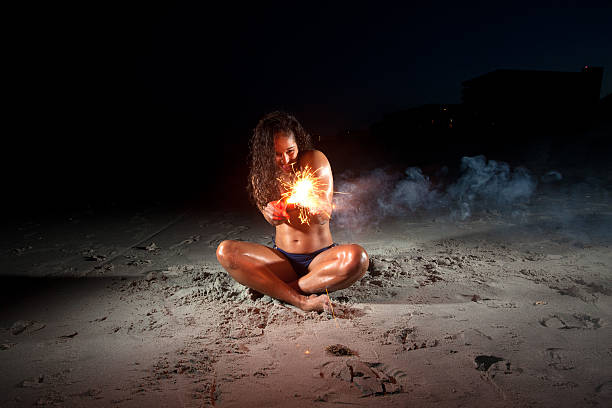 istock Young Brunette Woman playing with sparklers on beach 177044146