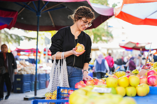 Woman with a net in her hand shopping for fruits and vegetables at the local public market