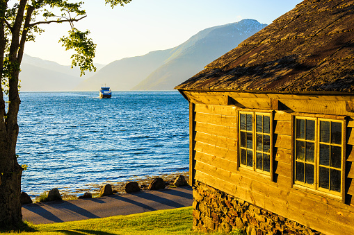 Passenger ferry is sailing through the Hardanger Fjord at sunset, Norway