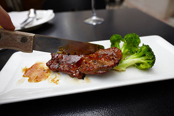Steak with broccoli on plate knife cutting
