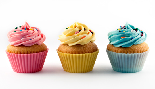 Studio shot of vanilla cupcakes with pink, yellow and blue frosting