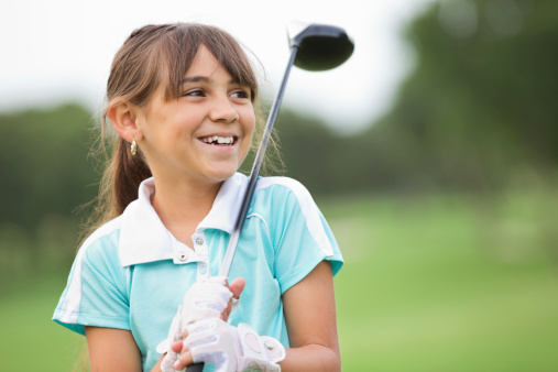Happy little girl playing golf at country club