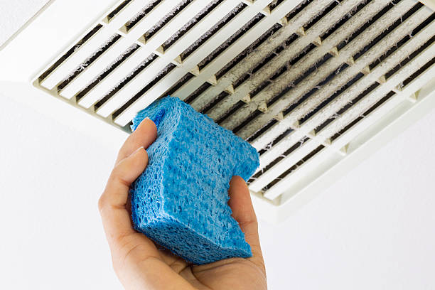 Cleaning Bathroom Fan Vent Cover with Sponge stock photo