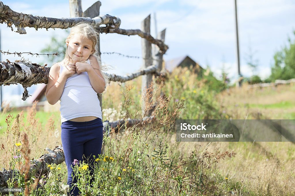 Vergüenza pequeña girl standing in front of rural valla - Foto de stock de Azoramiento libre de derechos