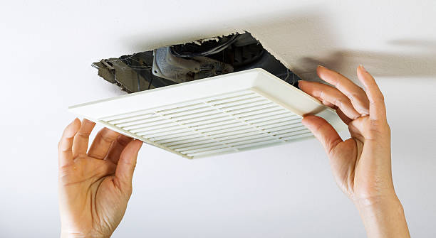 Removing Bathroom Fan Vent Cover to Clean Inside stock photo