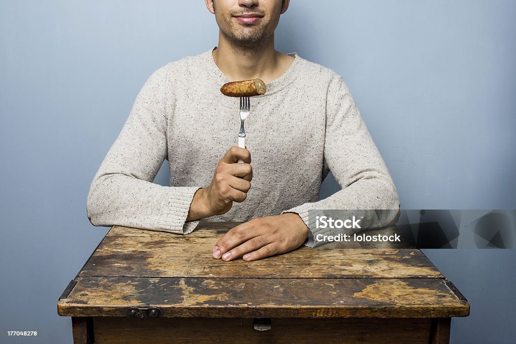 Giovane uomo che mangia una salsiccia - Foto stock royalty-free di Insaccato