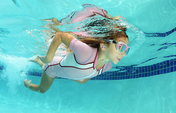 cute kid swimming in pool cute kid swimming underwater in pool ear plug stock pictures, royalty-free photos & images