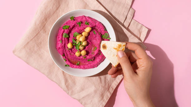 istock hand dipping pita bread in Beetroot hummus, top view 1770494559