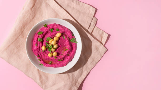 Beetroot hummus on pink background, top view