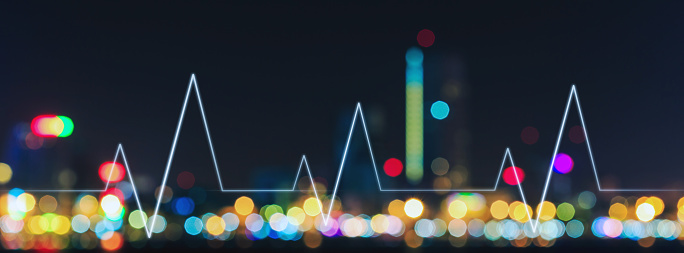 Abstract blurred city light with bokeh background at night against graphic interface of heart beat, city life concept, panorama view