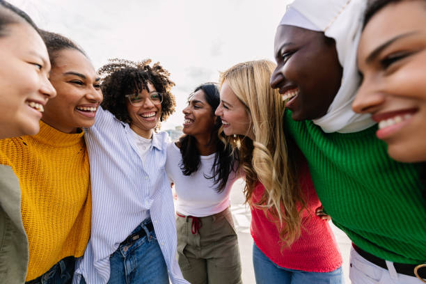 Seven happy young adult women from different cultures laughing together outdoors Seven happy young adult women from different cultures laughing together outdoors. Female friendship concept with diverse group of girls friends hugging each other having fun at city street religious institutions stock pictures, royalty-free photos & images