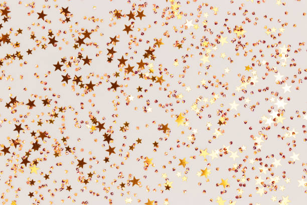 istock Glittering gold colored stars and crystals confetti on a gray background. 1770534933