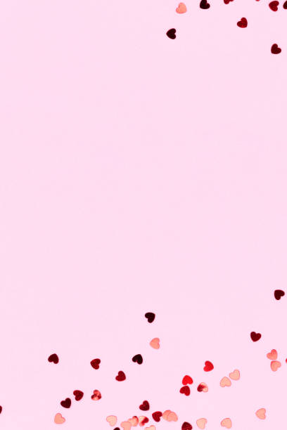 istock Metallic red confetti in a heart shape on a pink background. 1770541239