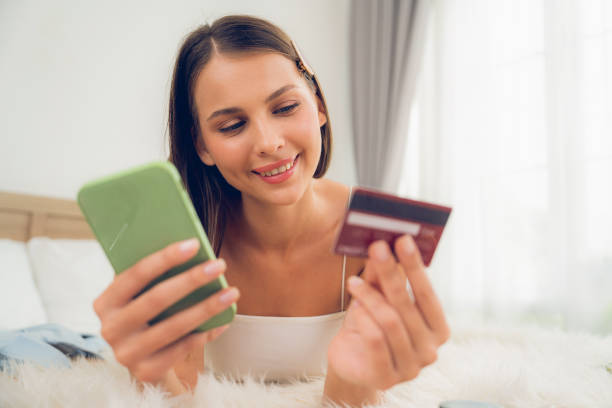 istock Young woman lying on bed using online payment app. Unveiling 1770546240