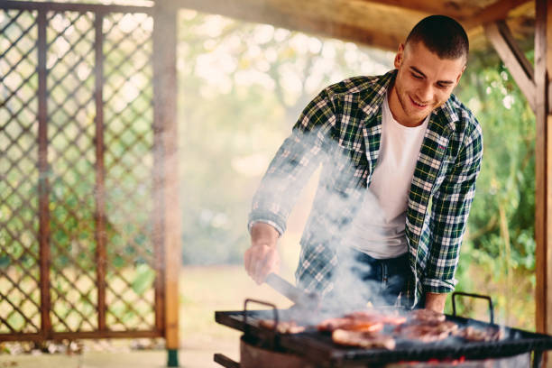 istock A smiling man making lunch outdoors, barbecuing, putting meat on the grill. 1770550623