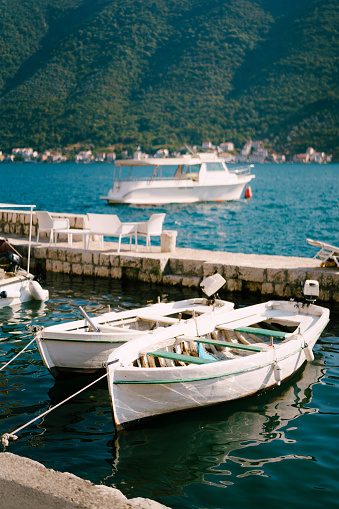 Fishing boats are moored to the shore between two piers. High quality photo