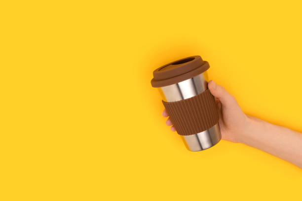 Female hand hold reusable coffee cup on a yellow background. Place for text.