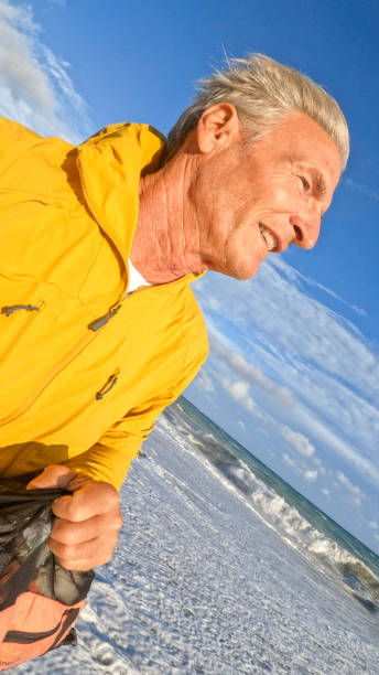 profilo laterale di uomo maturo che cammina lungo la costa - film tilt foto e immagini stock