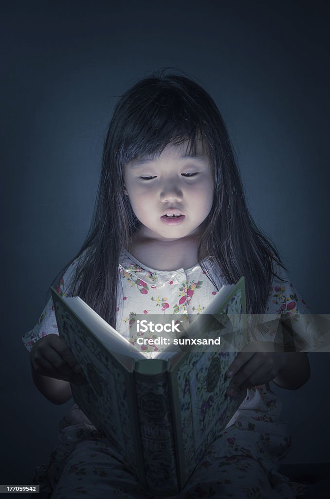 Ragazza lettura libro nel sfondo scuro - Foto stock royalty-free di Bambino