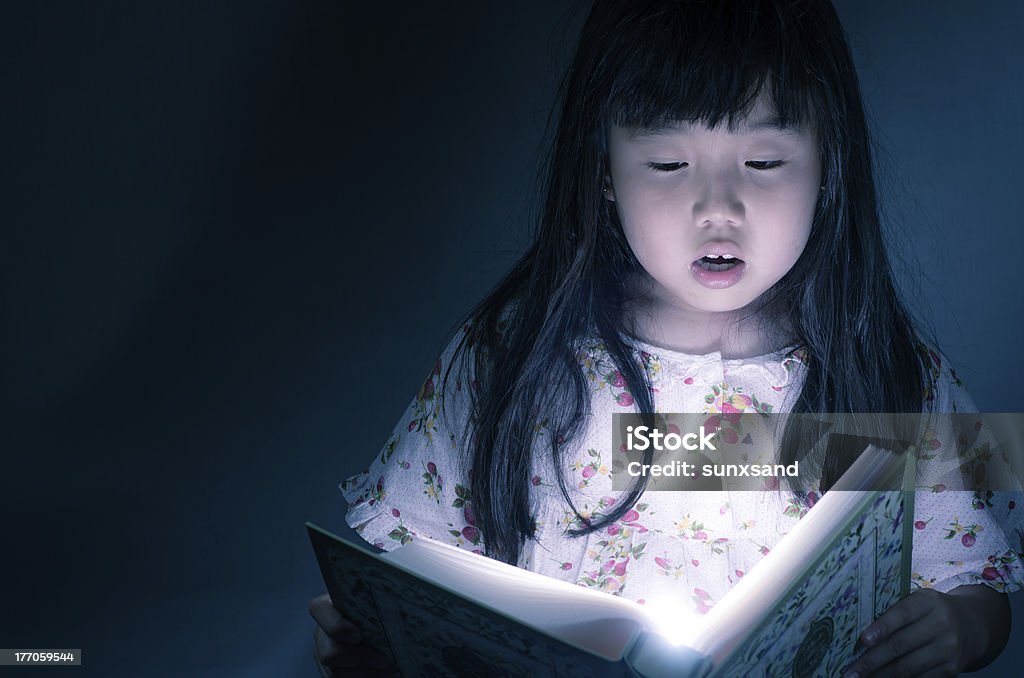 Mädchen liest ein Buch in der dunklen Hintergrund - Lizenzfrei Bibliothek Stock-Foto