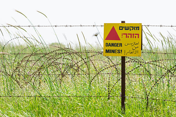 istock Razor wire guard fence and warning sign on mines field 177059997