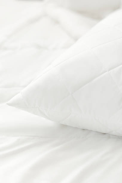 istock White quilted pillow on a white bedding white background. Cushion. Home textile. Macro photo 1770609513