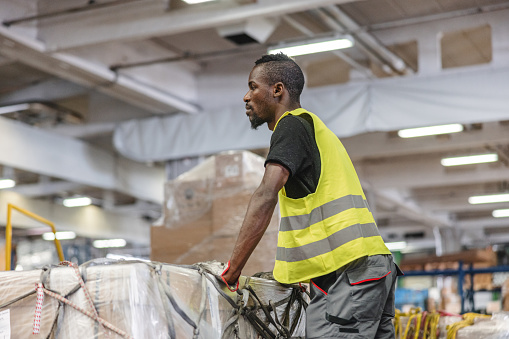 African American airport warehouse worker loading a truck with a cargo picked up at the airport.