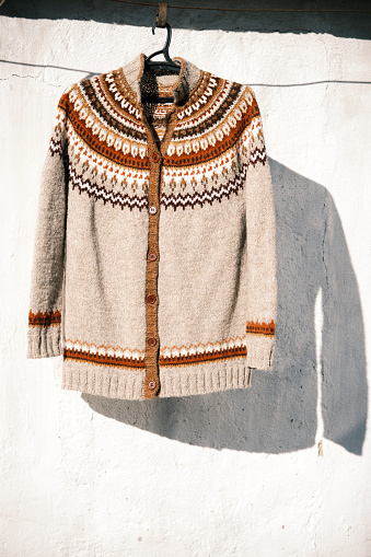 Handknitted woolen cardigan sweater is hanged in backyard
