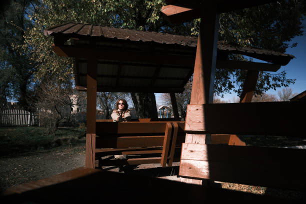 Single mature woman is walking alone in brightly lit autumn park