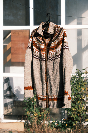 Handknitted woolen cardigan sweater is hanged in backyard