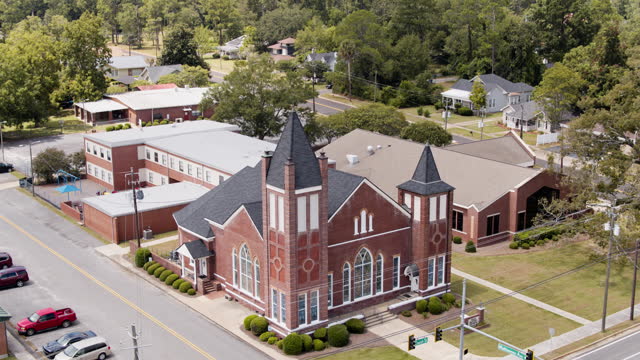 Main street of Pelham neighborhood in Georgia. School buildings surround First Baptist Church on Mathewson Ave. Aerial footage with forward-ascending-tilt down camera motion