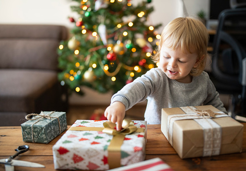 Cute little boy decorating the christmas presents.