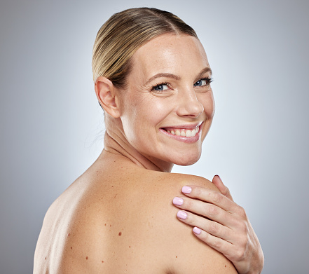 Portrait, beauty and skincare with a model woman touching her back in studio on a gray background. Health, wellness and cosmetics with an attractive young female posing to promote skin care
