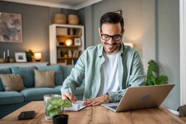 Portrait of handsome Caucasian man looking at laptop, working online from his home stock photo